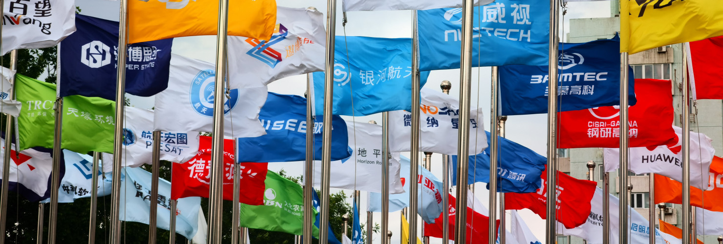 Factory flags of famous Chinese enterprises flutter in the wind under the blue sky in front of the square of the permanent site of the Zhongguancun Forum in Beijing, China, May 14, 2024.