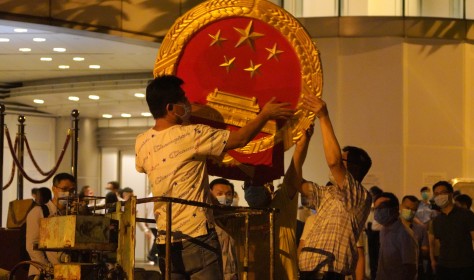 Workers place a national emblem outside the Metropark Hotel Causeway Bay